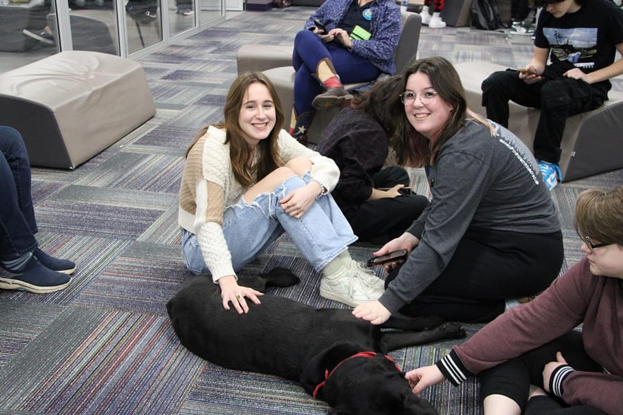 Eva Filippi and Lilly Collins, pet the schools service dog Brody. 
