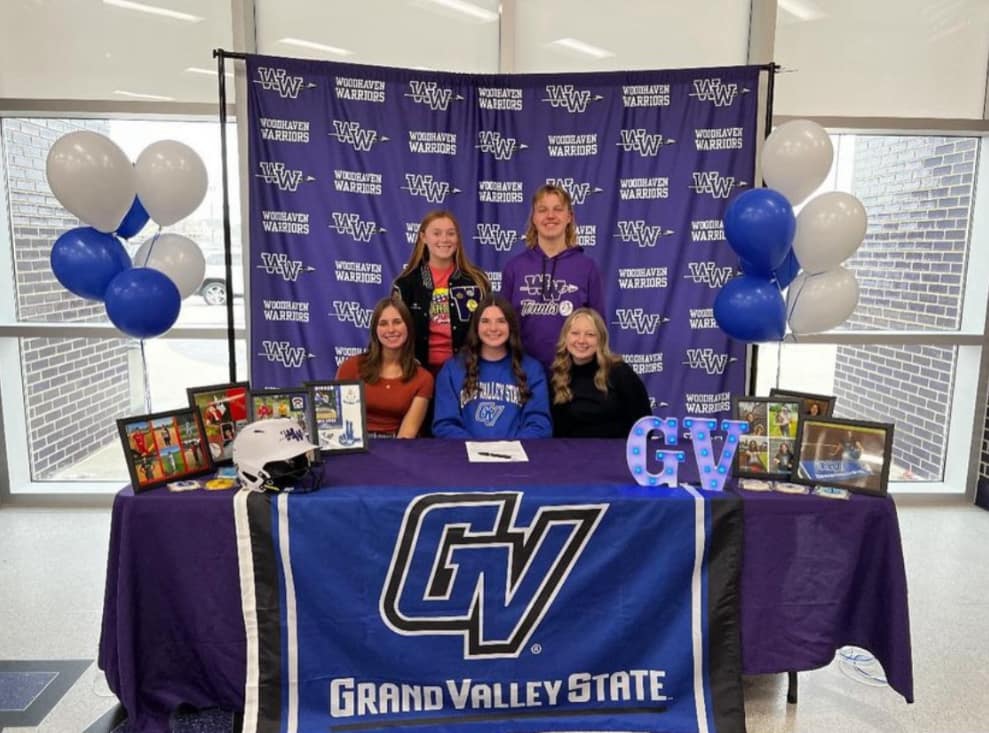 Surrounded by close friends, Grace Usher signs her commitment to play softball at Grand Valley State. 